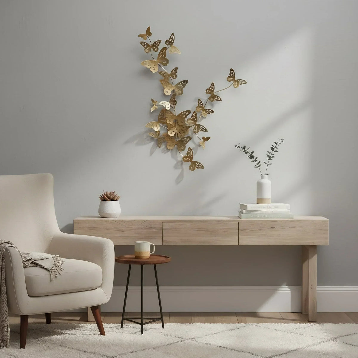 A gold-toned metal wall sculpture titled "Woven Wings," featuring an organic cluster of many small, stylized butterflies seemingly flying upward on a pale gray wall above a light wood console table.